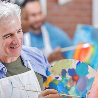 Senior man and mature woman enjoy painting together during art class.