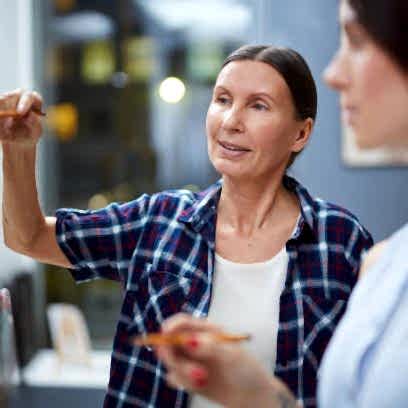 Aged teacher explaining to one of students how to mix colors